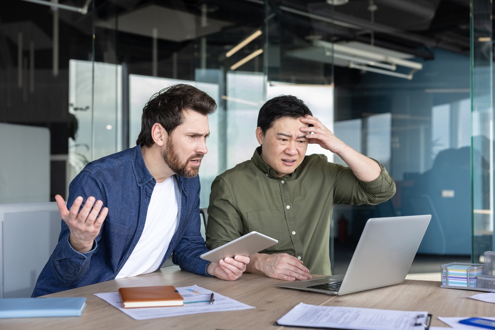 Two men react with concern after discovering risks that foreigners should consider when buying property in Thailand.